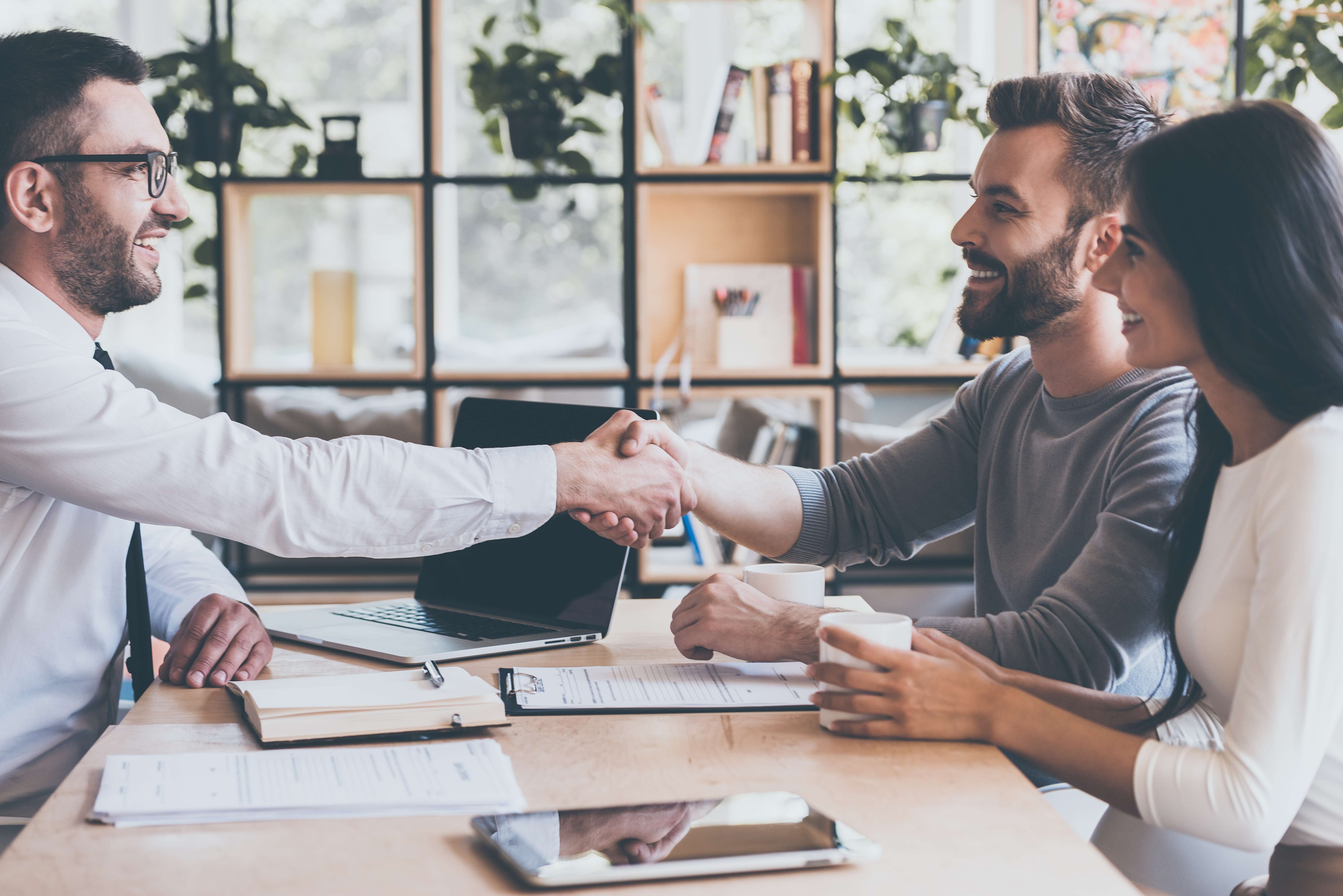 Real estate agent shaking hands with clients